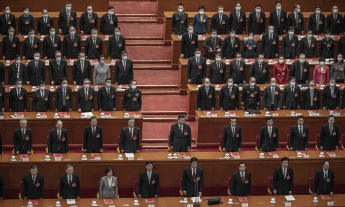 Le dirigeant chinois Xi Jinping (au centre) et les législateurs se lèvent pour l'hymne lors de la session de clôture de la conférence de la législature d'approbation automatique au Grand Hall du Peuple à Beijing, en Chine, le 11 mars 2021. (Kevin Frayer/Getty Images)