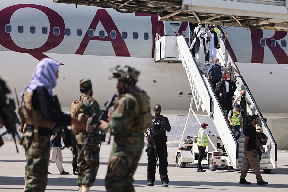 -Des combattants de l'unité militaire Taliban montent la garde alors que les passagers d'un avion de Qatar Airways débarquent à l'aéroport de Kaboul le 14 septembre 2021. Photo de Karim SAHIB / AFP via Getty Images.