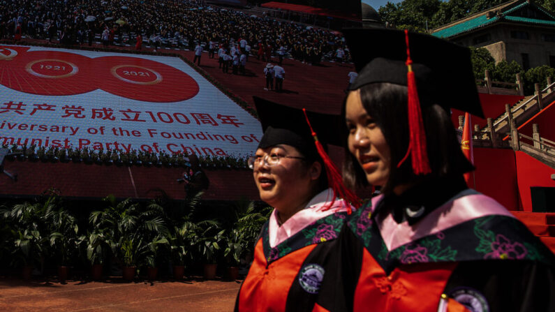 Deux diplômées passent devant un grand écran montrant le centenaire du PCC à l'université de Wuhan, à Wuhan, en Chine, le 23 juin 2021. (Getty Images)