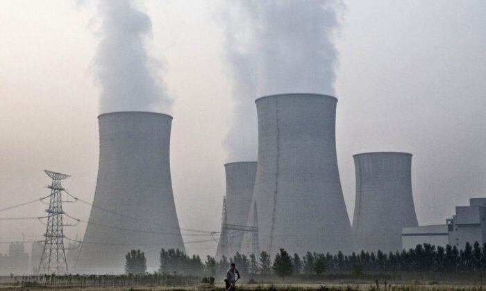 Un paysan travaille dans son champ à côté d'une centrale au charbon appartenant à l'État à Huainan, dans la province chinoise de l'Anhui, le 15 juin 2017. (Kevin Frayer/Getty Images)