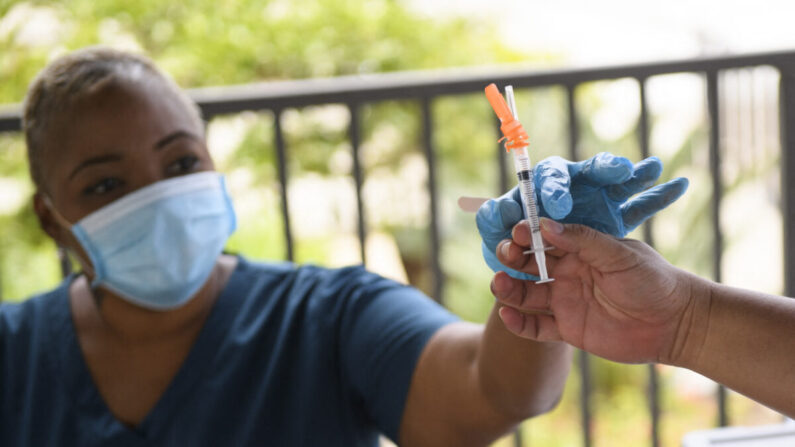 Une infirmière se fait remettre une dose du vaccin Pfizer Covid-19 avant de l'administrer à un étudiant au cours de la mission de vaccination mobile Covid-19 organisée par le service de santé publique de la Ville de Long Beach sur le campus de l'université d'État de Californie à Long Beach (CSULB), en Californie, le 11 août 2021. (Patrick T. Fallon/AFP via Getty Images)