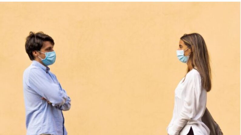 Un jeune couple en distanciation sociale portent un masque de protection et se regardent dans les yeux, concept de pandémie et de sentiments.