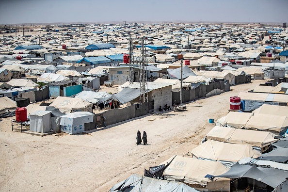 -Des femmes marchent parmi les abris du camp kurde d'al-Hol, qui abrite des proches de combattants présumés du groupe État islamique, dans le nord-est de la Syrie, le 2 août 2021. Photo de Delil SOULEIMAN / AFP via Getty Images.