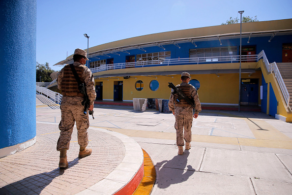 -Des soldats montent la garde devant un bureau de vote de l'école élémentaire  au Chili, le 20 novembre 2021, à la veille des élections générales chiliennes. Photo de JAVIER TORRES/AFP via Getty Images.