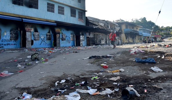 Un homme examine les dégâts à Honiara le 27 novembre 2021, alors qu'un calme tendu est revenu après des jours d'émeutes intenses. Photo de Charley PIRINGI / AFP via Getty Images.