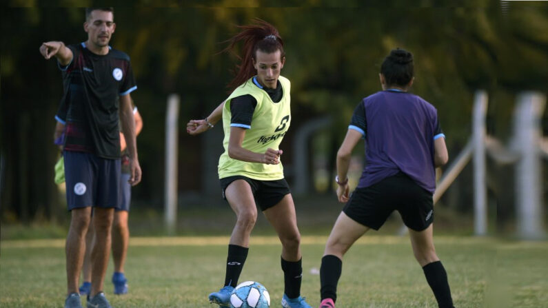 La joueuse de football transgenre argentine Mara Gomez (au centre) contrôle le ballon à côté de l'entraîneur Juan Cruz Vitale (à gauche) lors d'une séance d'entraînement avec son équipe de football féminine de première division, Villa San Carlos, à La Plata, Argentine, le 14 février 2020. (Photo par JUAN MABROMATA/AFP via Getty Images)