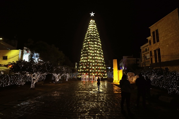 -Illustration- Une fille se tient devant un arbre de Noël dans l'ancien port libanais de Byblos le 9 décembre 2019. Photo de JOSEPH EID / AFP via Getty Images.