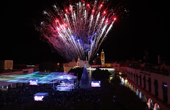 -Les Palestiniens regardent des feux d'artifice illuminer le ciel pour marquer l'allumage d'un arbre de Noël le 4 décembre 2021 sur la place de la Mangeoire près de l'église de la Nativité. Photo  Ahmad GHARABLI/AFP via Getty Images.