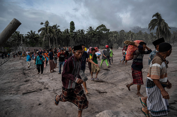 -Des villageois récupèrent leurs biens et fuient dans une zone couverte de cendres volcaniques à Lumajang le 5 décembre 2021, après l'éruption du volcan Semeru. Photo de Juni KRISWANTO / AFP via Getty Images.