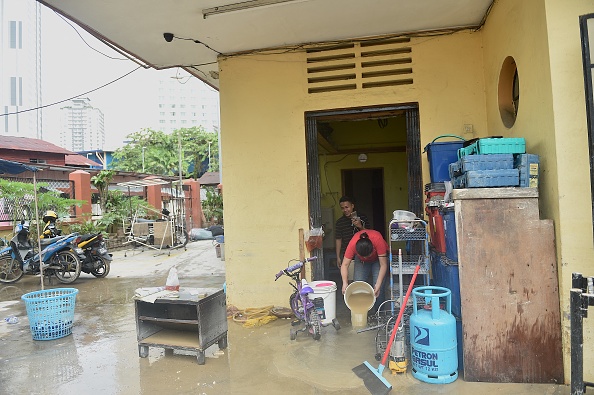 Des gens nettoient leur maison après qu'elle a été touchée par les inondations à Kuala Lumpur en Malaisie le 19 décembre 2021. Photo par Arif Kartono / AFP via Getty Images.