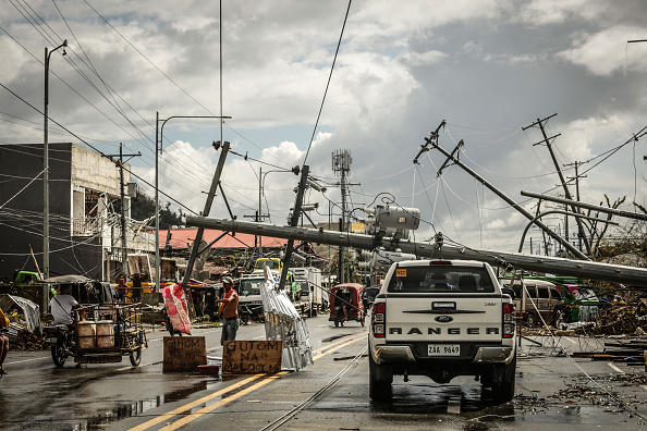 -Des pylônes électriques tombés bloquent une route tandis qu'un panneau demandant de la nourriture est affiché le long d'une route dans la ville de Surigao, le 19 décembre 2021. Photo Ferdinandh CABRERA / AFP via Getty Images.