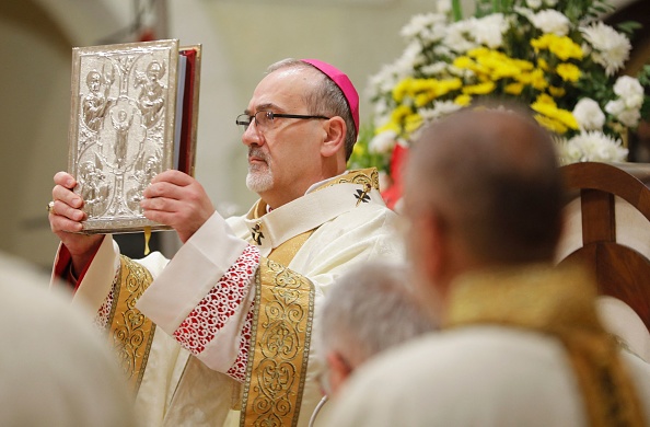 -Le patriarche latin par intérim de Jérusalem dirige une messe de minuit de Noël à l'église Sainte-Catherine, dans l'église de la Nativité, à Bethléem, le 25 décembre 2021. Photo de Mussa QAWASMA / POOL / AFP via Getty Images.