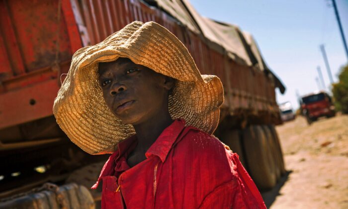 Un enfant passe devant un camion transportant des roches extraites d'une mine de cobalt dans une carrière de cuivre et de cobalt à Lubumbashi, en République démocratique du Congo, le 23 mai 2016. (Junior Kannah/AFP via Getty Images)