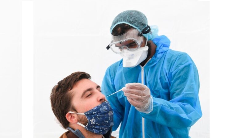 Un médecin avec un équipement de protection utilise un écouvillon pour effectuer un test PCR. (Photo par ALAIN JOCARD/AFP via Getty Images)