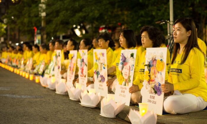 Des pratiquants de Falun Gong organisent une veillée à la bougie devant le consulat de Chine à Toronto, le 13 juillet 2019, en tenant des photos de pratiquants morts à cause de la persécution en Chine. (Handout)