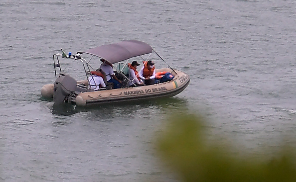 Des officiers de la marine brésilienne sont vus lors d'une opération de sauvetage au lac Furnas à Capitolio, dans l'État de Minas Gerais, au Brésil, le 9 janvier 2022, un jour après qu'un gros fragment de roche se soit détaché d'un ravin et ait plongé sur plusieurs bateaux de touristes, faisant au moins huit morts dans les canyons voisins du lac Furnas. (Photo par DOUGLAS MAGNO/AFP via Getty Images)