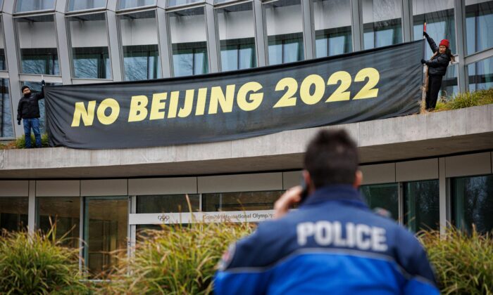 Un policier parle au téléphone alors que des militants tibétains de l'association Students for a Free Tibet accrochent une banderole lors d'une manifestation devant le siège du Comité international olympique (CIO) en prévision des Jeux olympiques d'hiver de février Pékin 2022, à Lausanne, le 11 décembre 2021. (Valentin Flauraud/AFP via Getty Images)