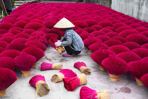 -Un ouvrier ramasse des bâtons d'encens séchés dans une cour du village de Quang Phu Cau à la périphérie de Hanoï le 12 janvier 2022, avant les célébrations du Nouvel An lunaire. Photo de NHAC NGUYEN / AFP via Getty Images.