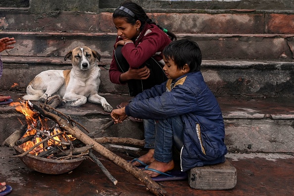 - Des enfants sont assis à côté d'un feu de joie pour se réchauffer près des rives de la rivière Yamuna par une froide matinée d'hiver à New Delhi le 23 janvier 2022. Photo de SAJJAD HUSSAIN / AFP via Getty Images.