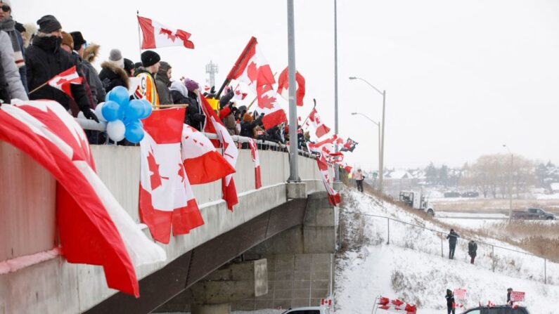 Les partisans d'un convoi de camionneurs roulant de la Colombie-Britannique à Ottawa pour protester contre l'obligation vaccinale pour les camionneurs transfrontaliers, au niveau d'une passerelle d'autoroute à non loin de Toronto, Ontario, Canada, le 27 janvier 2022. (Photo par COLE BURSTON/AFP via Getty Images)