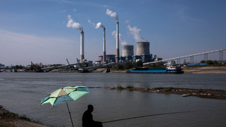 Des habitants sont assis au bord de la rivière en train de pêcher près d'une centrale électrique au charbon, le 11 novembre 2021 à Hanchuan, dans la province de Hubei, en Chine. (Photo by Getty Images)