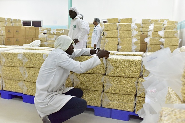 -Un homme marque des sacs de noix de cajou transformées dans une usine de la ville de Bouaké, dans le centre de la Côte d'Ivoire, le 24 mai 2018. Photo par ISSOUF SANOGO / AFP via Getty Images.