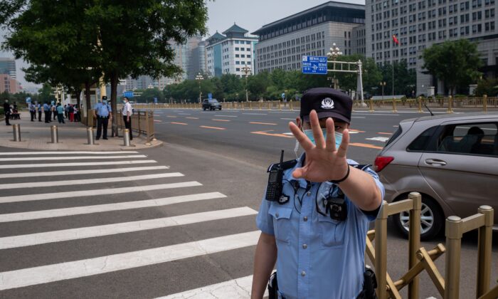 Un policier sécurise une zone et intervient avant le passage d'un convoi de bus transportant des délégués, avant la cérémonie d'ouverture de la Conférence consultative politique du peuple chinois (CCPPC) à Pékin, le 21 mai 2020. (Photo par NICOLAS ASFOURI / AFP) (Photo par NICOLAS ASFOURI/AFP via Getty Images)