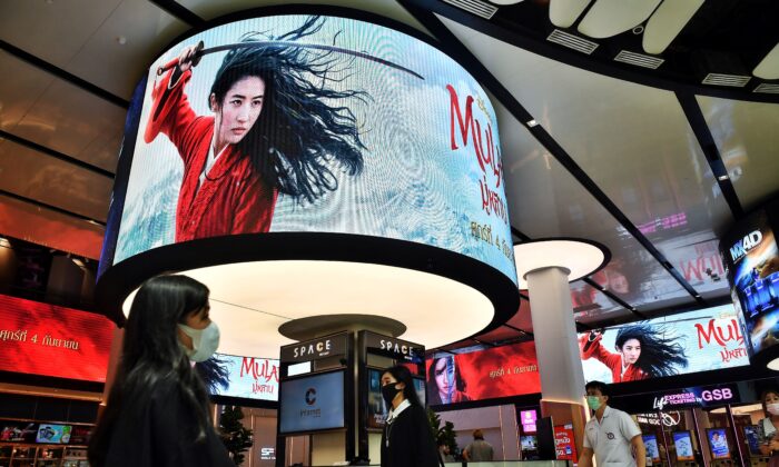 Passants devant les panneaux publicitaires du film Mulan de Disney dans un cinéma à l'intérieur d'un centre commercial à Bangkok, le 8 septembre 2020. (LILLIAN SUWANRUMPHA/AFP via Getty Images)