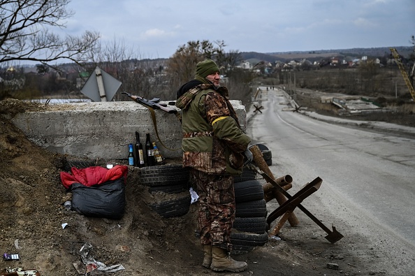 Un militaire ukrainien monte la garde à un poste de contrôle à côté du dernier pont sur la route qui relie Stoyanka à Kiev, le 6 mars 2022. Photo par ARIS MESSINIS/AFP via Getty Images.