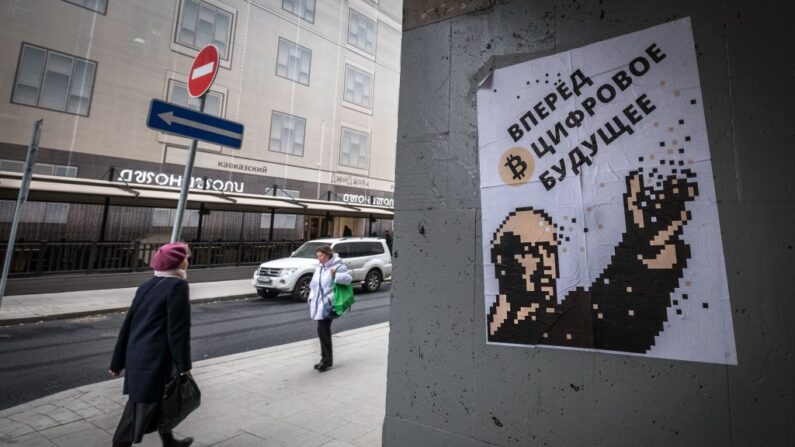 Une femme passe près d’une affiche montrant Vladimir Lénine à côté d’un Bitcoin et indiquant : "Allez de l'avant dans l'avenir numérique", centre-ville de Moscou, le 29 septembre 2017. (YURI KADOBNOV/AFP via Getty Images)