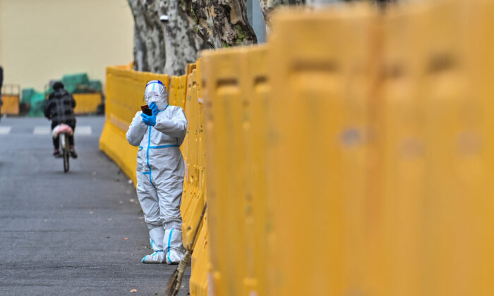 Un ouvrier vêtu d’un équipement de protection, à côté des barrières interdisant l’accès à certains quartiers pendant le confinement de Shanghai, le 31 mars 2022. (Photo par HECTOR RETAMAL/AFP via Getty Images)