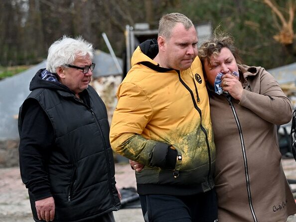 Une mère ukrainienne est réconfortée par des proches après la découverte du corps de son fils dans une fosse d'une station-service à la périphérie du village de Buzova, à l'ouest de Kiev, le 10 avril 2022. Photo de Sergei SUPINSKY / AFP via Getty Images.