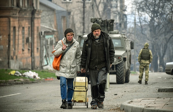 Les gens marchent dans le centre-ville de Marioupol le 12 avril 2022, les troupes russes intensifient une campagne pour prendre la ville portuaire stratégique, dans le cadre d'une attaque massive de l'est de l'Ukraine. Photo par Alexander NEMENOV / AFP via Getty Images.