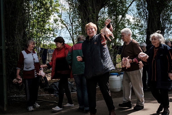 -Des personnes déplacées reçoivent des poulets à l'entrée du bunker d'une usine, dans l'est de l'Ukraine, le 27 avril 2022. Photo de YASUYOSHI CHIBA/AFP via Getty Images.