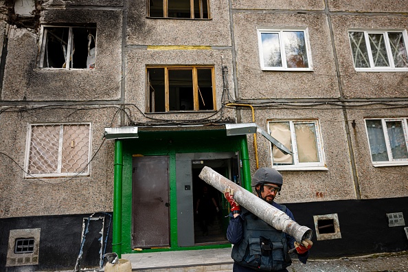 Un membre d'une équipe de déminage du Service d'urgence transporte une partie d'un missile à la suite d'un bombardement russe à Kharkiv, dans l'est de l'Ukraine, le 28 avril 2022. Photo de Dimitar DILKOFF/AFP via Getty Images.