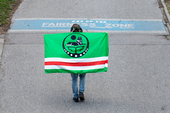 -Un jeune Tchétchène anonyme porte un drapeau de la Tchétchénie alors qu'il marche près du canal du Danube à Vienne le 4 février 2022. Photo par ALEX HALADA/AFP via Getty Images.