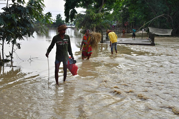 Des villageois ont pataugé dans les eaux de crue après de fortes pluies dans le district de Hojai, dans l'État d'Assam, le 21 mai 2022. Photo de Biju BORO / AFP via Getty Images.