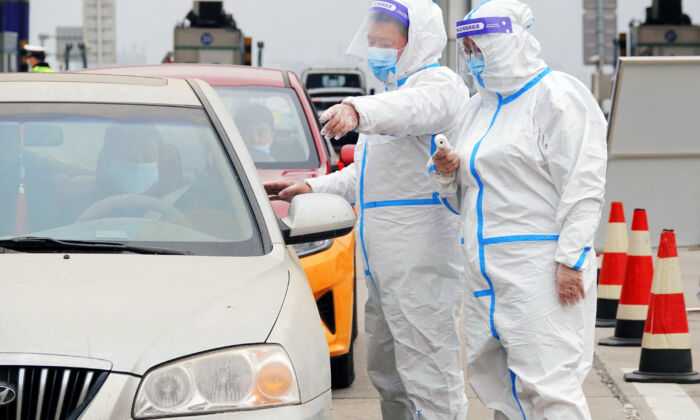 Agents de santé vérifiant les résultats des tests PCR des automobilistes et leurs codes santé, à la sortie de Yantai, dans le Shandong, le 16 mars 2022. (STR/AFP via Getty Images)