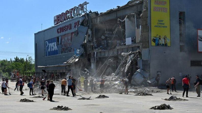 Des travailleurs communaux nettoient les décombres d'un supermarché, partiellement détruit par une attaque de missiles dans la banlieue sud-est de la ville ukrainienne de Kharkiv, le 8 juin 2022(Photo par SERGEY BOBOK/AFP via Getty Images)