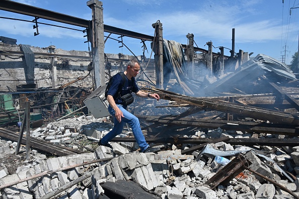 Un homme marche à travers les décombres d'un bâtiment détruit à l'usine de Mashgidroprivod, après une attaque de missile russe à Kharkiv le 29 juin 2022. Photo de SERGEY BOBOK/AFP via Getty Images.