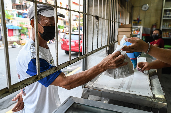 Un homme achète le populaire petit-déjeuner pandesal dans une boulangerie de Manille, le 20 juillet 2022.  Photo de JAM STA ROSA/AFP via Getty Images.