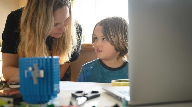 James Laurie, 8 ans, est aidé dans son travail en ligne par sa mère Laurette alors qu'il poursuit sa scolarité à domicile, à Londres, le 25 janvier 2021. (Leon Neal/Getty Images)