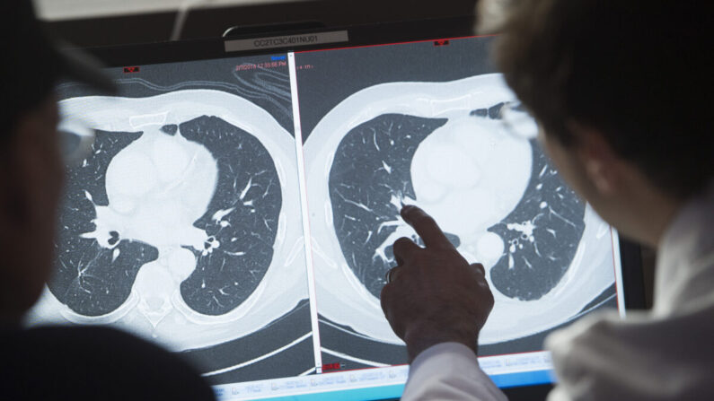 Le Dr Christian Hinrichs, chercheur du National Cancer Institute dans le domaine de l'immunothérapie pour les cancers liés au VPH+, montre à un patient, survivant d'un cancer métastatique, la différence entre son scanner de tumeurs cancéreuses (à dr.) et un scanner impeccable après traitement (à g.), à l'Institut national de la santé (NIH) à Bethesda, Md, le 8 février 2018. (Saul Loeb/AFP via Getty Images)