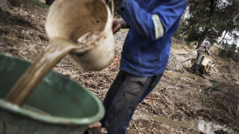 Des mineurs illégaux passent au tamis des monticules de pierres inutilisées pour trouver de la poussière d'or, qui est alors vendue à des acheteurs qui la traitent ensuite pour en extraire des particules d'or et les agglomérer. Photo d'archive de 2015. (John Wessels/AFP via Getty Images)