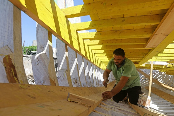 -L'artisan syrien Khaled Bahlawan enfonce des clous dans un bateau en bois dans son chantier naval sur l'île méditerranéenne syrienne d'Arwad le 24 juillet 2022. Photo de LOUAI BESHARA/AFP via Getty Images.