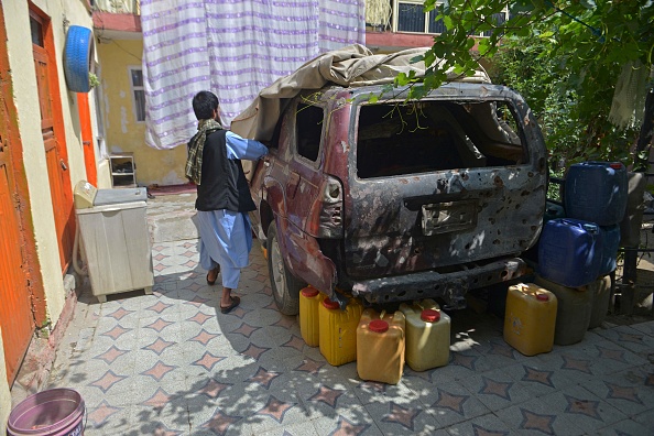 Nasratullah Malikzada, le neveu d'Aimal Ahmadi, enlève la bâche d'une voiture qui a été endommagée lors d'une frappe de drone américain, à Kaboul. Photo par AHMAD SAHEL ARMAN/AFP via Getty Images.