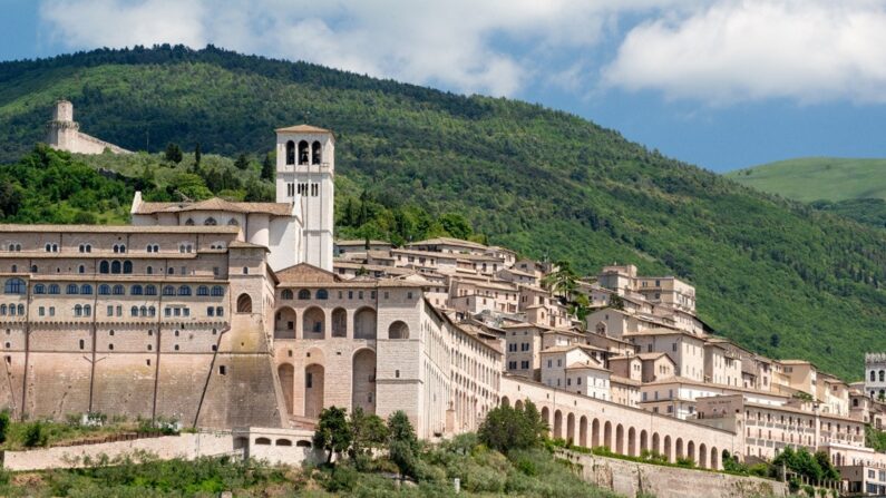 La ville médiévale d'Assise ainsi que les bâtiments résidentiels et religieux se trouvent sur les pentes du mont Subasio, derrière la ville. L'imposante cloche blanche de la basilique domine le paysage urbain. La façade de la basilique est fabriquée de pierres colorées provenant du mont Subasio. La façade reflète une couleur rose pendant le jour et une couleur blanche au clair de lune. Simone di Pucciarello, une riche citoyenne d'Assise, a fait don du terrain pour la basilique, une colline autrefois connue sous le nom de "colline de l'enfer" où les criminels étaient exécutés. Aujourd'hui, elle est connue comme la "Colline du Paradis". (Avec l'aimable autorisation de Peter K. Burian, CC BY-SA 4)