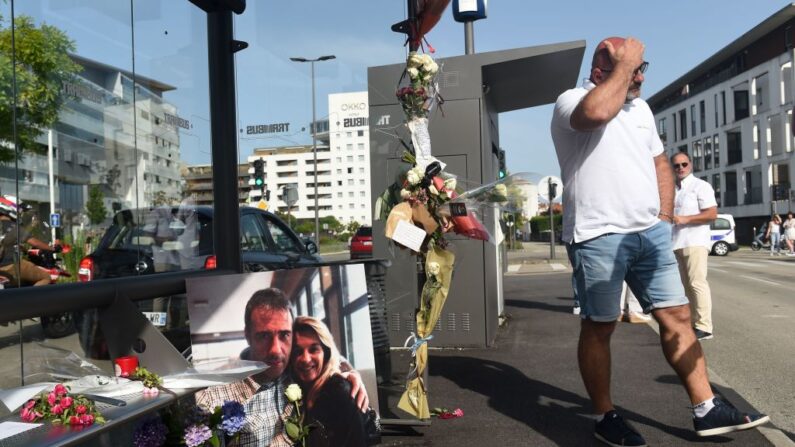 Un homme passe devant une photo de Véronique Monguillot et Philippe Monguillot, un chauffeur de bus déclaré en état de mort cérébrale après avoir été attaqué pour avoir refusé de laisser monter à bord un groupe de personnes qui ne portaient pas de masque de protection, affichée lors d'une marche blanche à Bayonne, dans le sud-ouest de la France, le 8 juillet 2020. (Photo by GAIZKA IROZ/AFP via Getty Images)