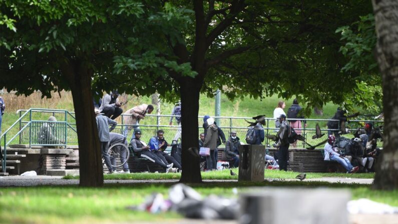 Des personnes sont assises sur des bancs après avoir été déplacées près de la Porte de la Villette, dans le nord de Paris, le 24 septembre 2021, après une opération de police visant à expulser les consommateurs de crack du quartier des Jardins d'Éole. (Photo by CHRISTOPHE ARCHAMBAULT/AFP via Getty Images)