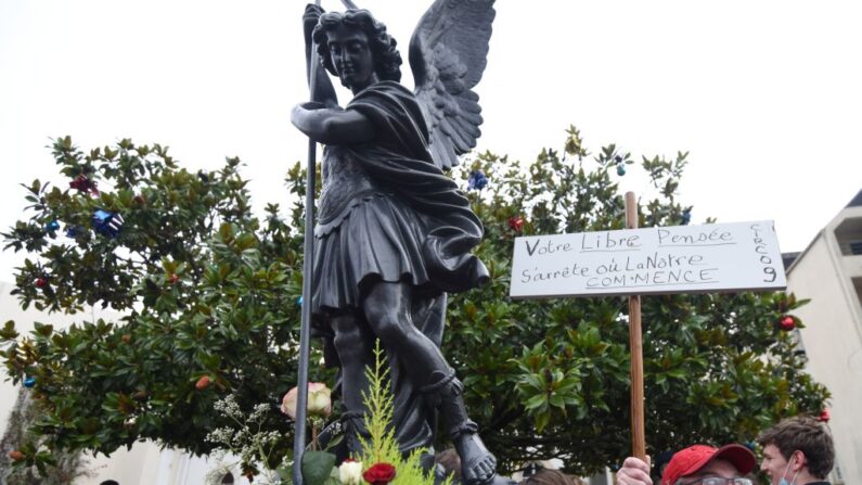 Un homme tient une pancarte à côté de la statue de Saint-Michel aux Sables-d'Olonne le 8 janvier 2022. (Photo by SEBASTIEN SALOM-GOMIS/AFP via Getty Images)